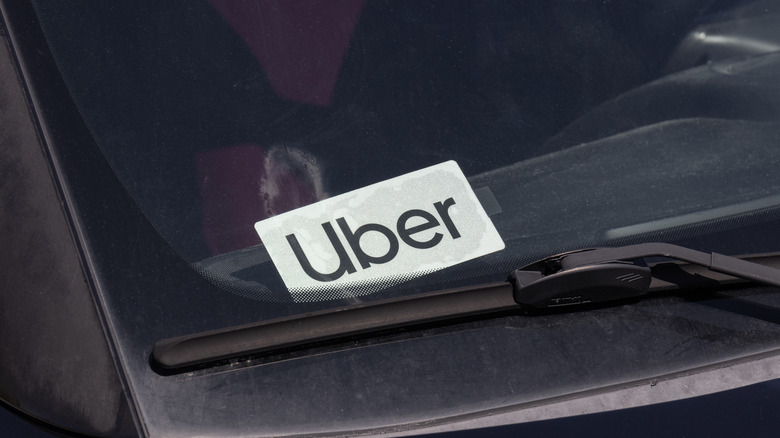 An Uber sign sits in the windshield of a rideshare car.