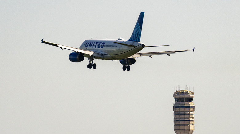 A United Airlines Airbus A319 plane flies over the air traffic control (ATC) tower while landing at Ronald Reagan National Airport (DCA) using the River Visual approach to Runway 19, on June 30, 2026 in Washington, DC.