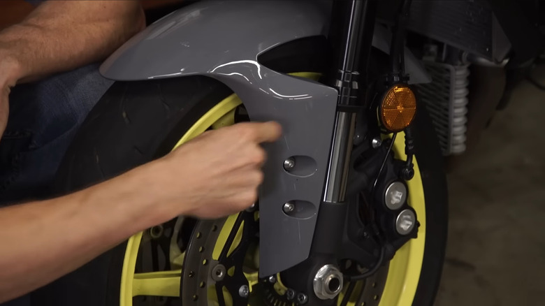 A man pointing toward an inverted motorcycle fork