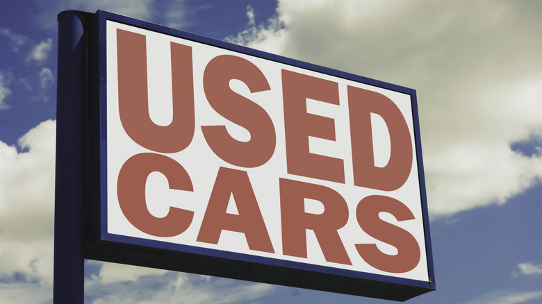 Vintage "used cars" backlit sign against a blue sky.