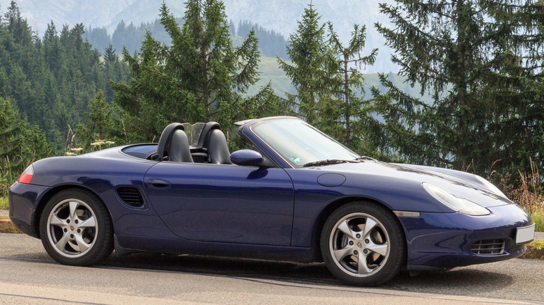 Dark blue convertible first-generation Porsche Boxster parked on the side of a mountain road