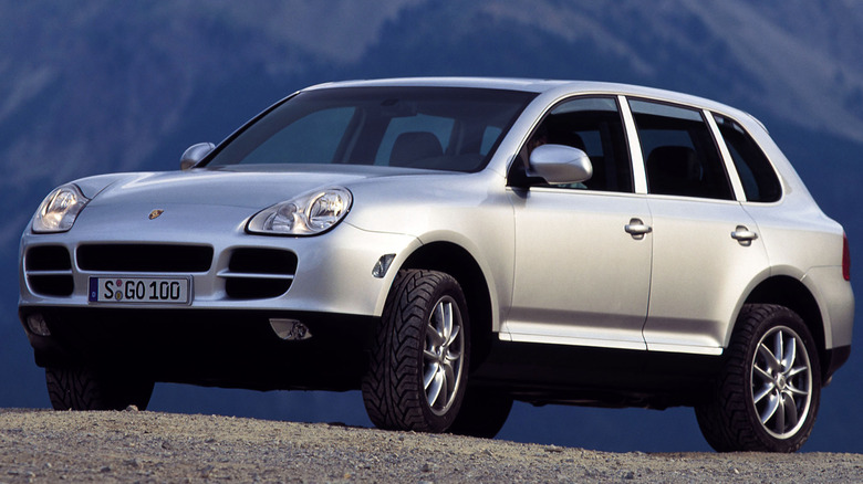 Silver 2003 Porsche Cayenne on display off-roading in front of mountains