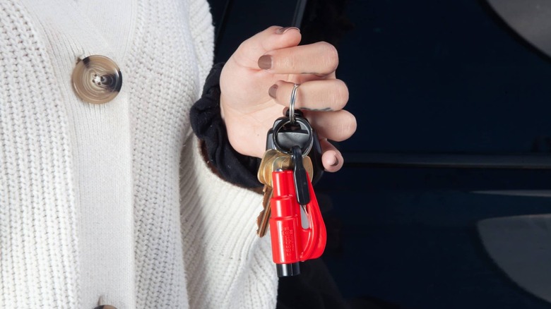 Resqme car escape tool attached to a keychain held in hand.