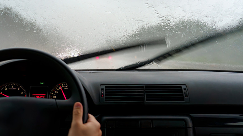 Behind the wheel of a Volkswagen Auto Group vehicle in intense rain, wipers in action.
