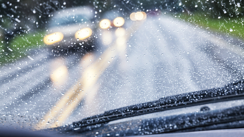 A blurry shot of oncoming cars with their headlights on in the rain.