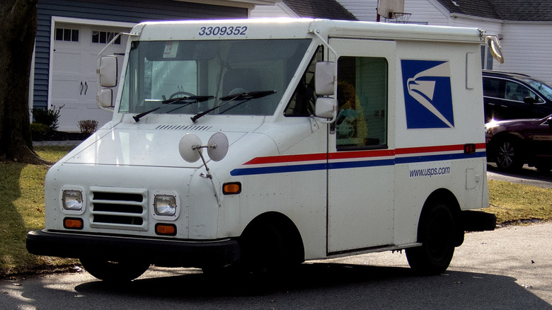 A Grumman LLV mail truck parked in front of a house in a neighborhood