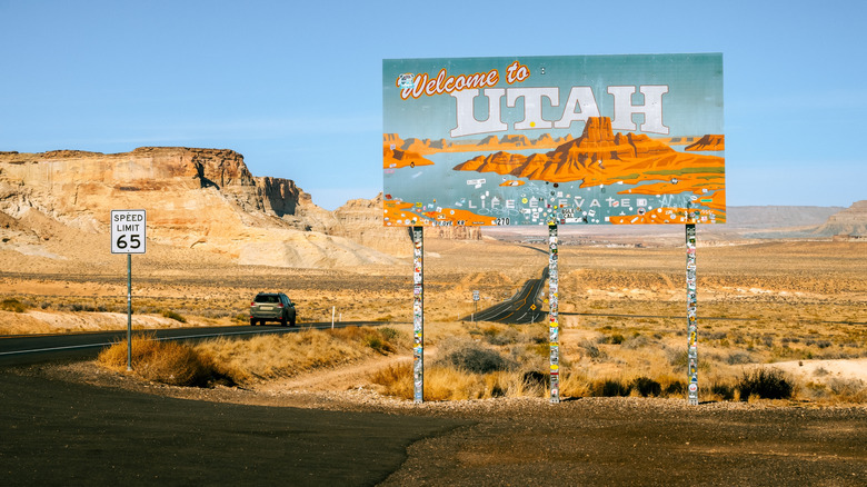 A "Welcome to Utah" sign with a car driving by on the highway