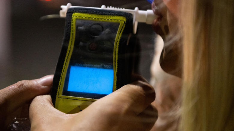 A woman blowing into a breathalyzer test