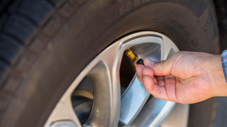 a person removing a valve stem cap from a tire's valve stem