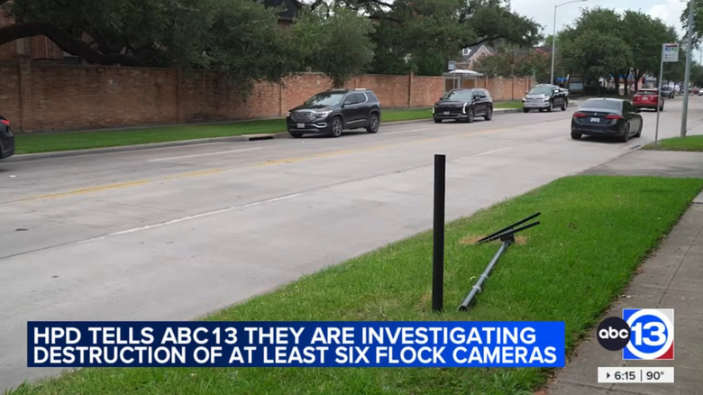 A quiet four-lane road with a random flock pole cut in half, the half with the camera is on the grass beside the road.