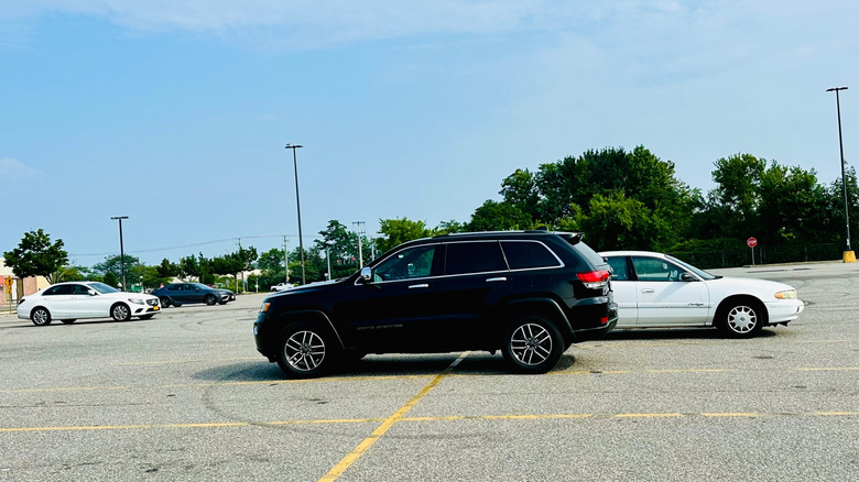 Black SUV parked across multiple spots in parking lot