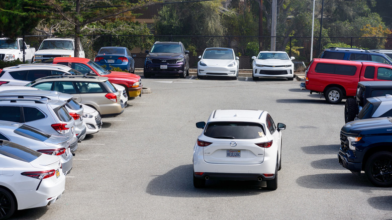 White Mazda SUV driving in parking lot looking for a space