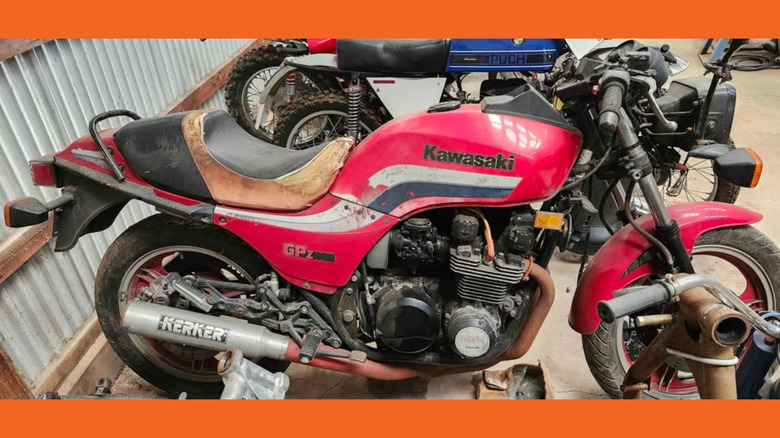 Red motorcycle in disrepair in a garage