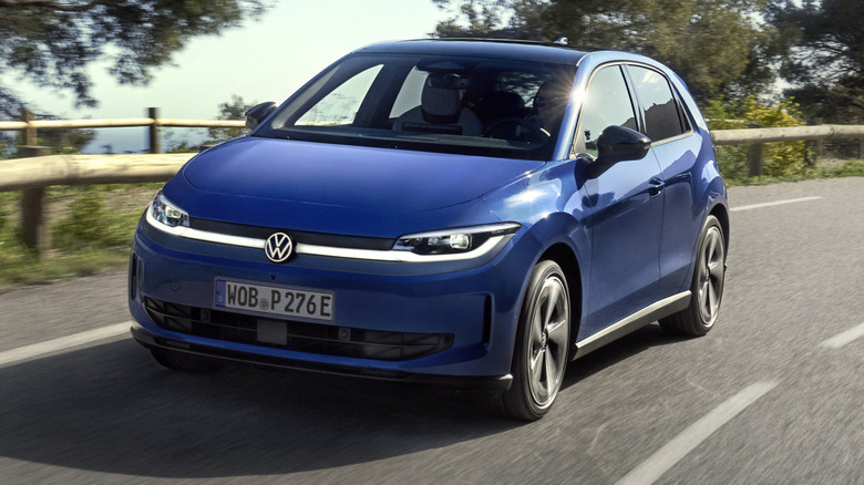 A front three-quarters shot of a blue ID Polo driving on a road in front of trees