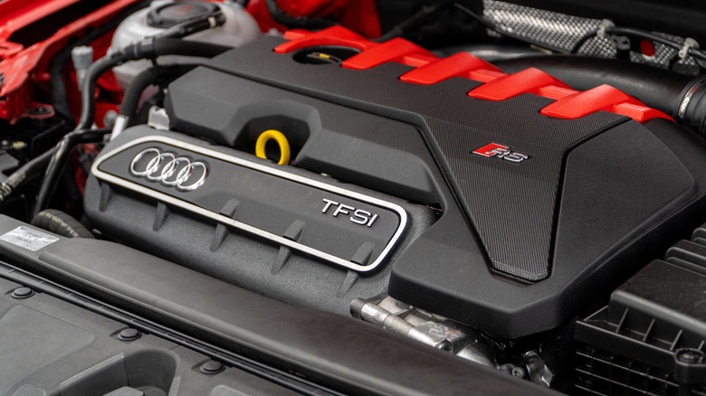 An Audi RS five-cylinder TFSI engine cover with red details.