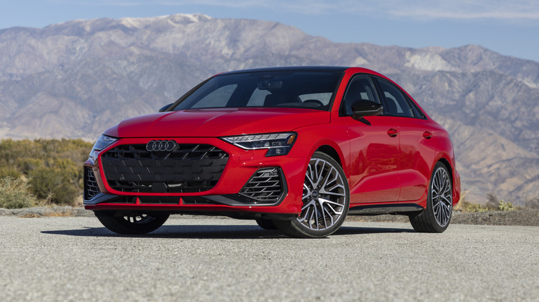 A red 2025 Audi S3 sedan parked in a remote location with mountains in the background.