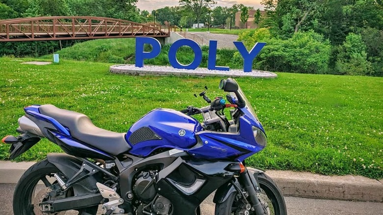 A blue Yamaha FZ6 in front of a sign that just says POLY