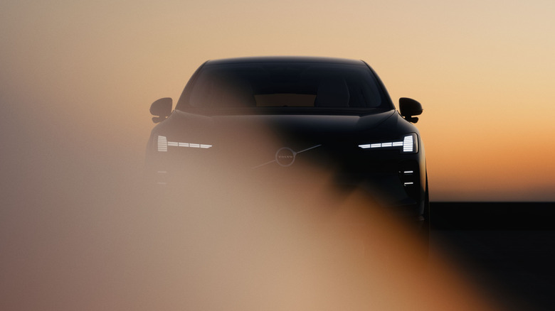 A teaser shot of the Volvo EX60 showing the Thor's Hammer headlight design and few other details in front of a peach colored background