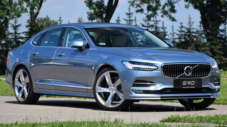 A 2016 Volvo S90 parked on a road with lots of greenery around.