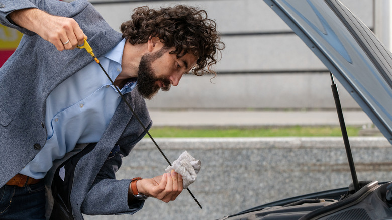 Man using a dipstick to measure a car's engine oil level