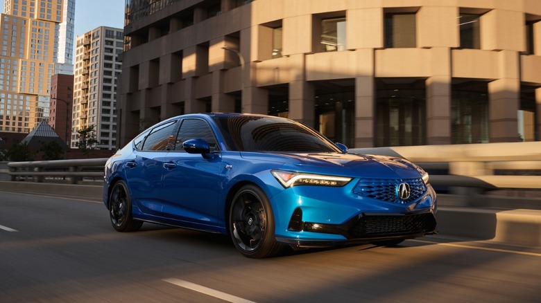 A blue 2026 Acura Integra A-Spec driving on a city street at sunset