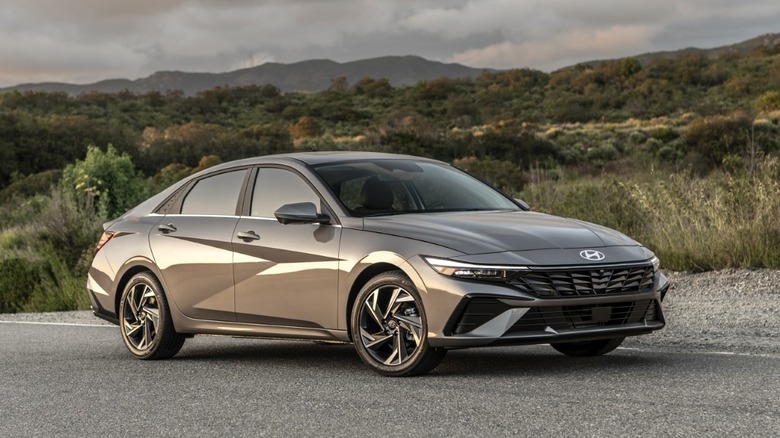 A shimmering silver 2025 Hyundai Elantra parked on the side of a rural road during golden hour.