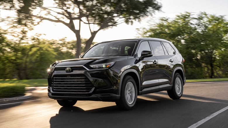 A 2026 Toyota Grand Highlander XLE driving on a tree-lined road during the day.