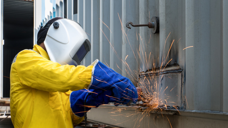 A technician cutting/welding on a metal structure.
