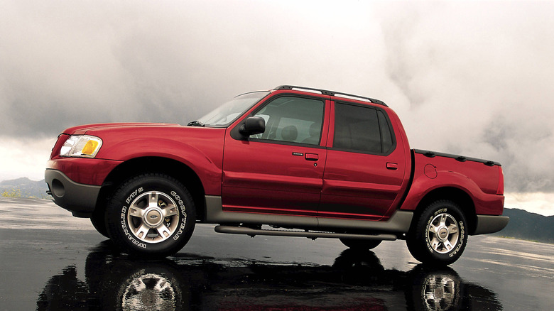 A first-generation red Ford Explorer Sport Trac sitting on wet tarmac under brooding skies, ready to take its occupants on their next adventure.
