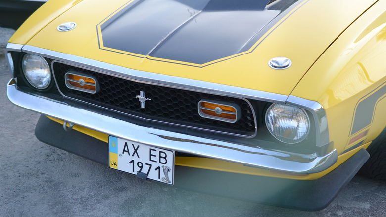 Front grille and emblem close-up of a yellow 1971 Ford Mustang.