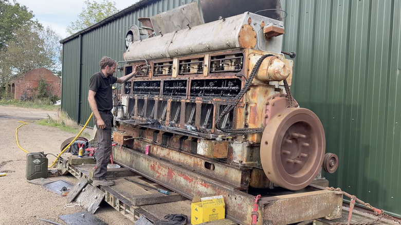 A 102.4-liter Mirrless generator engine, shown to scale towering over a man.