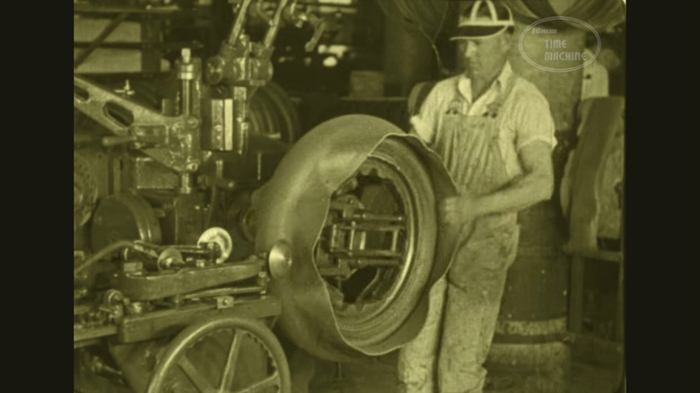 Another sepia-tone image from the film of a man forming a rubber ring around what will become a tire for a car.