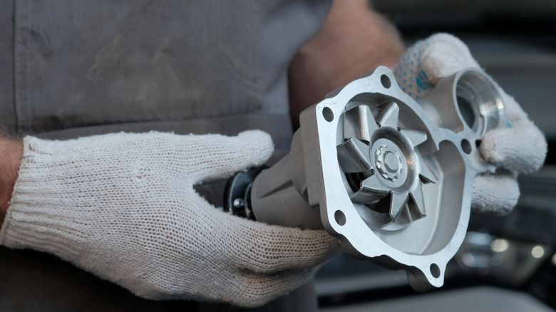 A mechanic holds up a new water pump