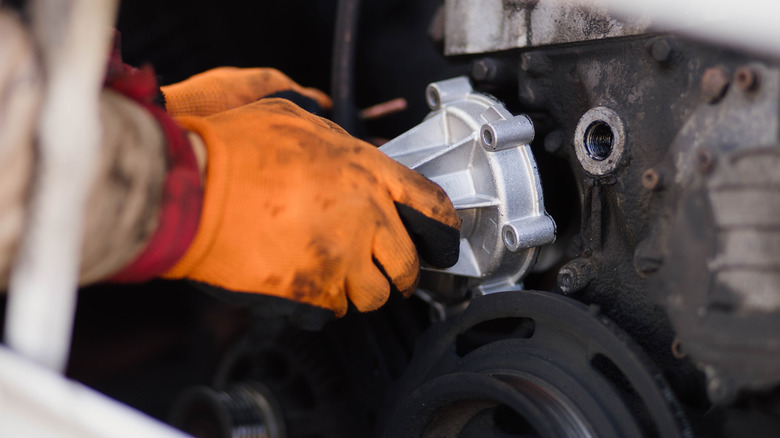 A mechanic installing a car's new water pump