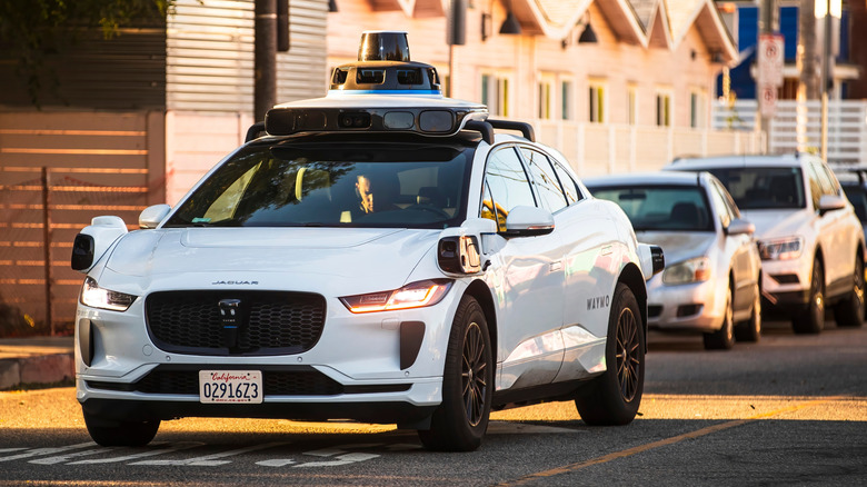 A Waymo self-driving Jaguar I-PACE navigates a city street.