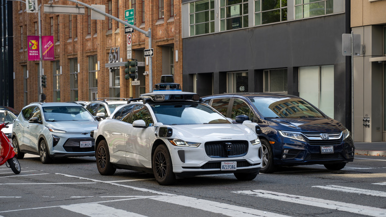 Waymo self-driving car with roof-mounted sensors stopped at intersection among city traffic, San Francisco, California, August 29, 2025