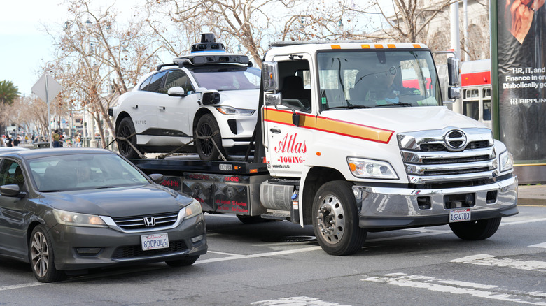 A broken down Waymo on the back of a tow truck in San Francisco.