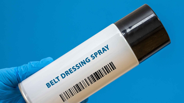 A gloved hand holding belt dressing spray