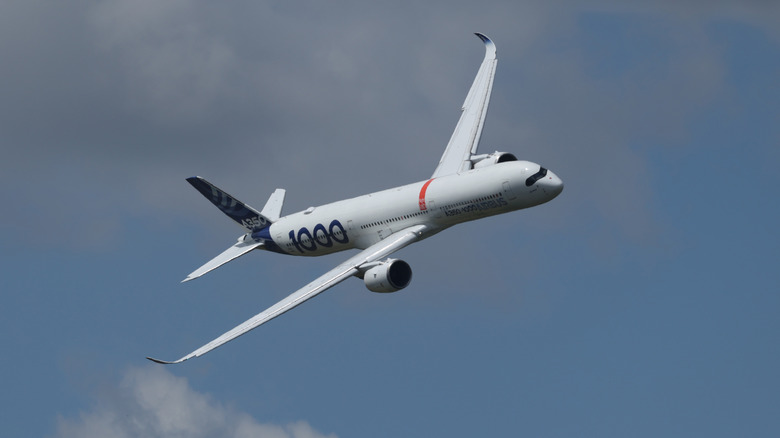An Airbus A350-1000 in flight against a partly cloudy sky