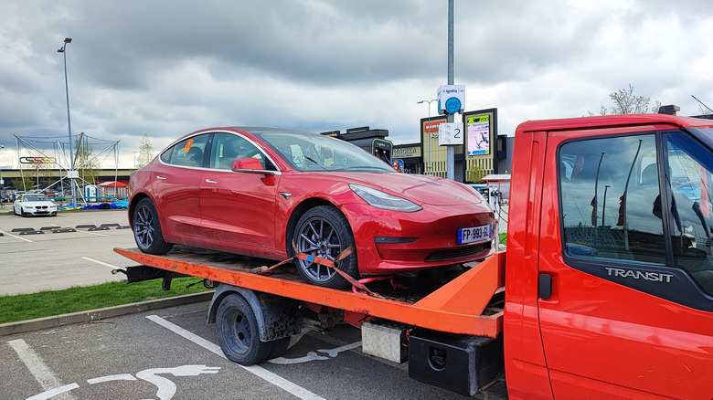 A Tesla Model 3 on the back of a flatbed truck.