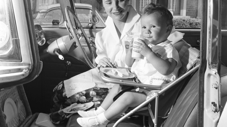 Baby being fed while sitting in vintage car child seat