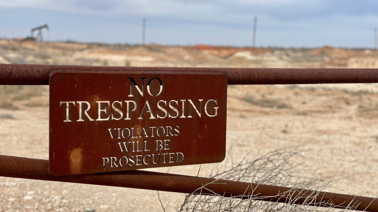 "No Trespassing" sign hangs on a metal gate outside of a Permian Basin oil site.
