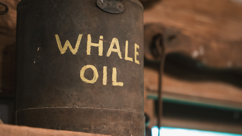 An old, rusted container of whale oil sits in front of a blurry old western-style room