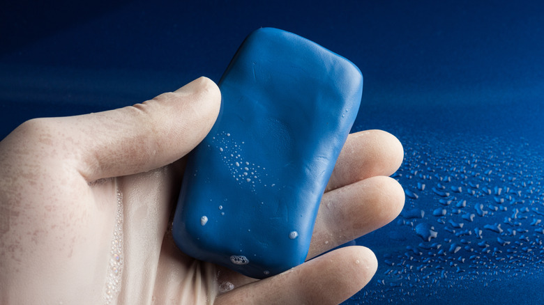 A hand holding a blue clay bar