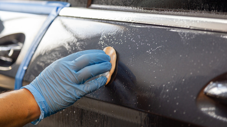 A detailer using the clay bar on the car door