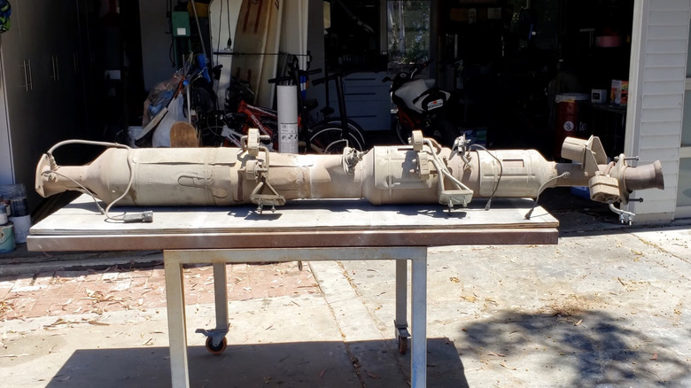 An exhaust assembly with the DPF filter laid out on a table outside a DIY garage.