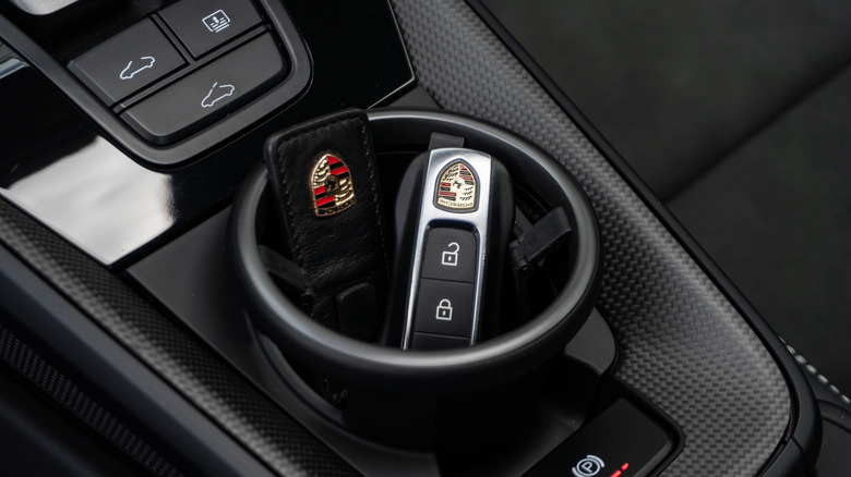 A Porsche 911 key fob in a carbon fiber cup holder, with center console detail