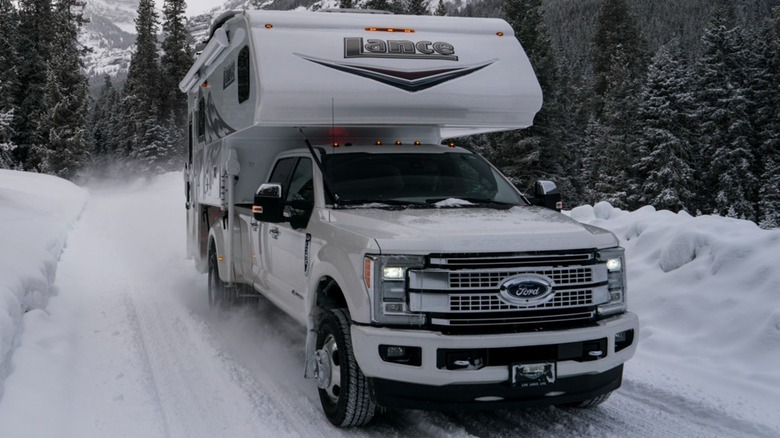 An RV drives across a snow-covered mountain road.