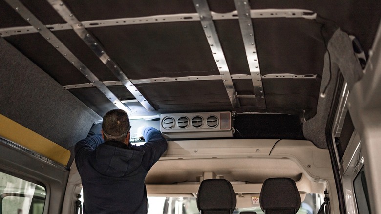 A man installs insulation in a conversion van.