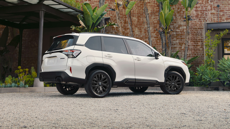 A right-side view of a 2026 Subaru Forester Onyx Edition parked in front of plants and a brick building